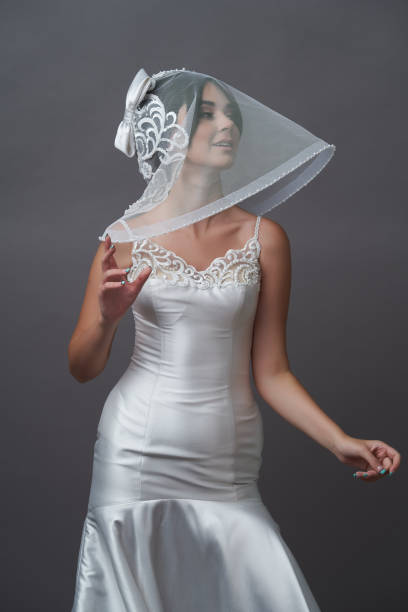 istock Beautiful bride in wedding dress posing on grey background with copy space. 1283014798
