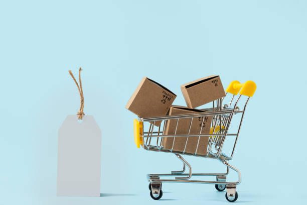istock Toy shopping cart with boxes and empty tag on blue background. Copy space for text or design. Sale, discount, shopping and delivery concept. Consumer society trend. 1283016336