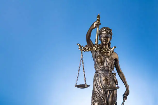 The blindfold goddess of justice Themis or Justitia on blue background