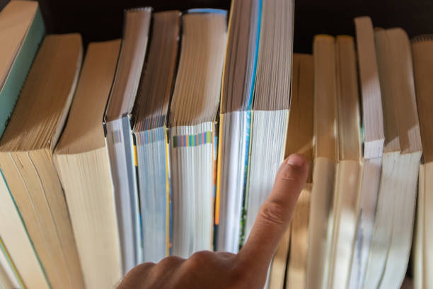 istock Hand choosing a book from a line of books 1283020411