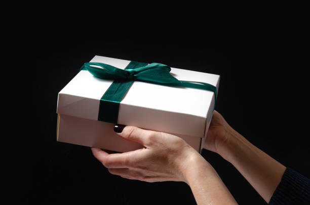 istock A woman holds a gift in her hands on a black background 1283021049