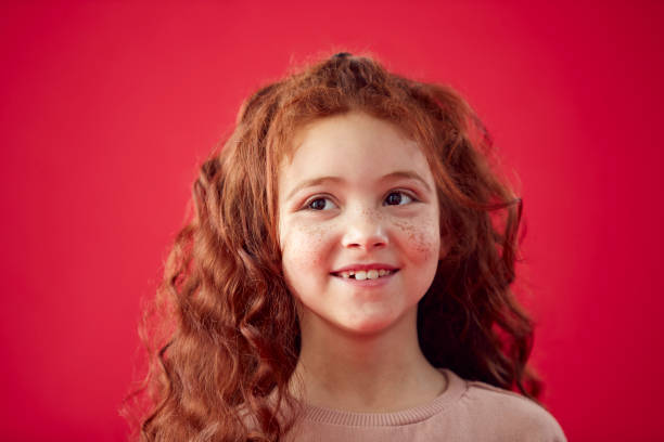 retrato de menina com cabelos longos e vermelhos contra fundo do estúdio vermelho sorrindo para a câmera - long red hair - fotografias e filmes do acervo
