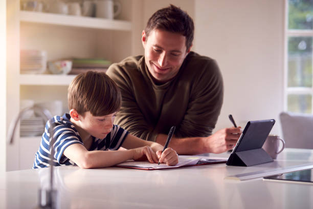 istock Father Helping Son With Homework Sitting At Kitchen Counter Using Digital Tablet Together 1283023757