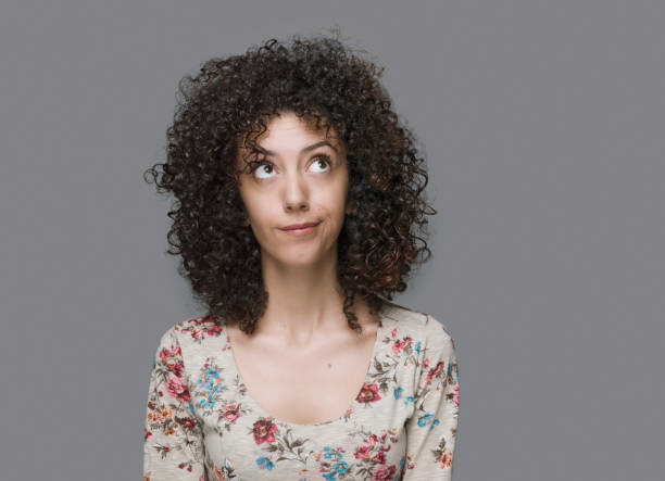 istock Curly haired young woman portrait with a curious face expression 1283023932