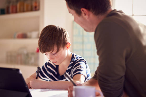 istock Father Helping Son With Homework Sitting At Kitchen Counter Using Digital Tablet Together 1283024733