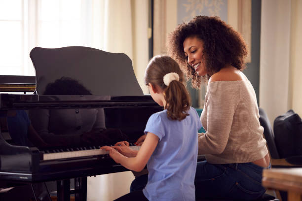 junge mädchen lernen, klavier zu spielen mit lektion von weiblichen lehrer - practicing piano child playing stock-fotos und bilder