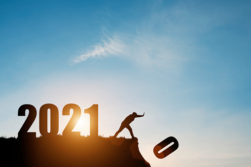 El hombre empuja el número cero por el acantilado donde tiene el número 2021 con el cielo azul y el amanecer. Es símbolo de inicio y bienvenida feliz año nuevo 2021. photo