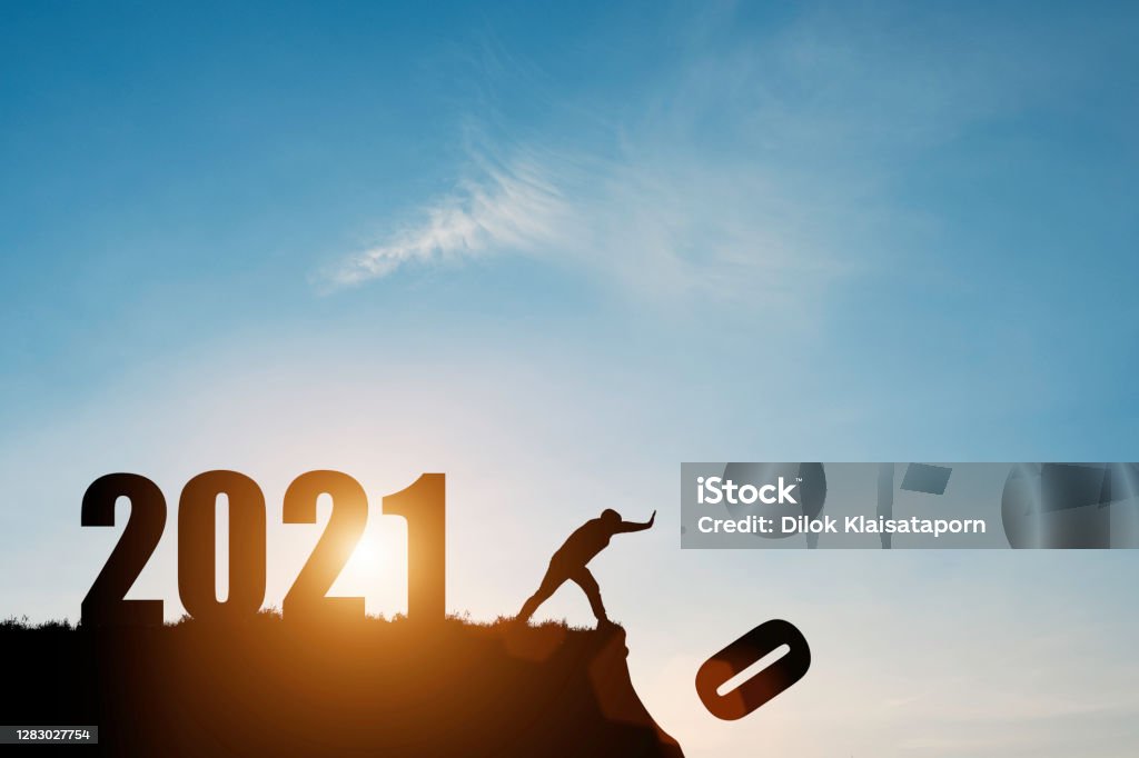 Man push number zero down the cliff where has the number 2021 with blue sky and sunrise. It is symbol of starting and welcome happy new year 2021. 2021 Stock Photo