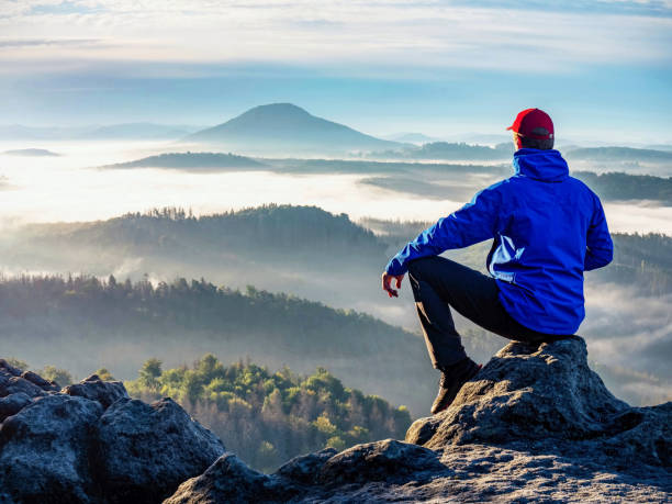 istock Man sit alone on the cliff with beautiful sunrise landscape 1283028085