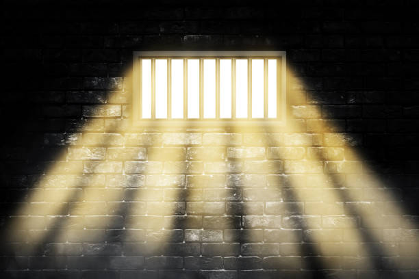 istock Prison inside interior with sunlight lighting through window on black brick wall grunge background. 1283029119