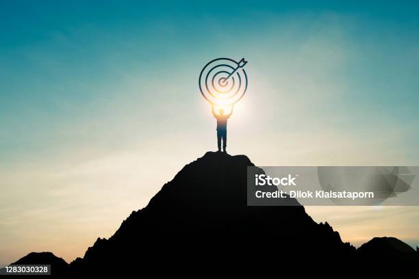 Silhouette Of Businessman Holding Target Board On The Top Of Mountain With Over Blue Sky And Sunlight It Is Symbol Of Leadership Successful Achievement With Goal And Objective Target Stock Photo - Download Image Now