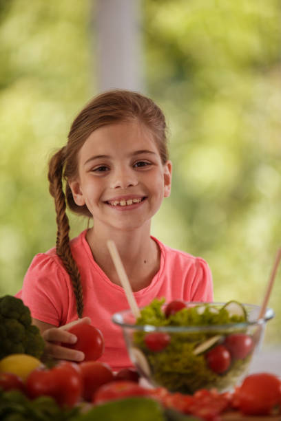istock Little cute girl smiling and looking at camera while preparing a salad 1283030547