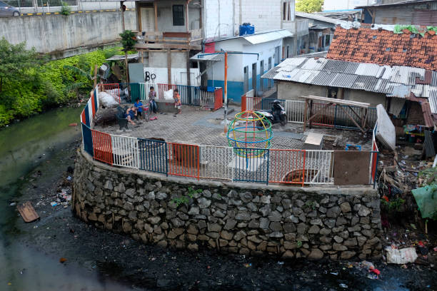 Playground near a polluted river Jakarta/Indonesia, October 2, 2020: Children play at a small playground near a heavy polluted river. jakarta slums stock pictures, royalty-free photos & images