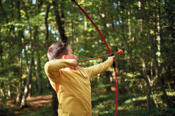 istock 6-7 years old child on nature and using archery bow 1283038878