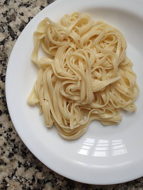 istock Top view of a plate with boiled pasta, on a marble surface.  Background image for recipes, cooking, preparing food and concepts about carbohydrates, sport and healthy eating. 1283041677