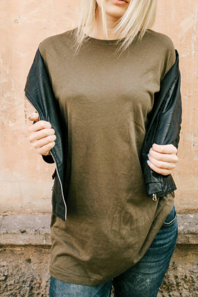 아름다운 젊은 금발 소녀 에 a 빈 녹색 군사 t 셔츠 와 가죽 재킷 와 청바지 - wall women leather street 뉴스 사진 이미지