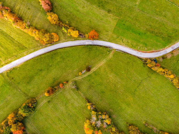 istock Winding Country Road Through Meadows in Autumn From Directly Above 1283044432