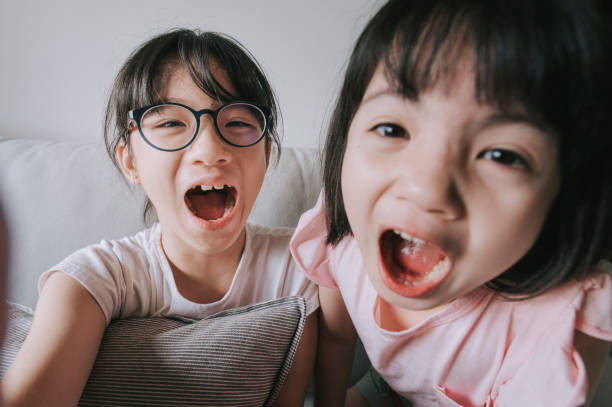 asiatische chinesische junge mädchen sprechen mit ihrem vater mit digitalen tablet online im wohnzimmer auf dem sofa glücklich - webcam fotos stock-fotos und bilder