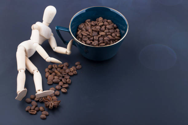 istock Roasted coffee beans and wooden doll on dark background. 1283048183