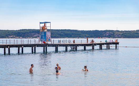 Portorož, Slovenia - August 18, 2020: A picture of a small group of people bathing on the beach of Portorož.
