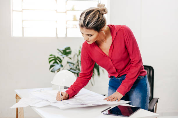 istock Young architect working in her office. Reviewing architectural design. 1283048741