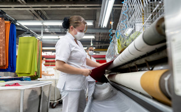 Mexican Women carrying a fresh batch of cookies on oven trays in bakery workshop.