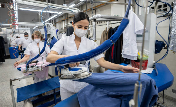 istock Women working at a laundromat wearing facemasks and ironing clothes 1283048960