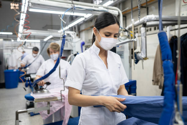 istock Woman working at a laundromat wearing facemasks and ironing clothes 1283048976