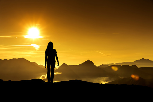 Woman looks at a sunrise in the mountains