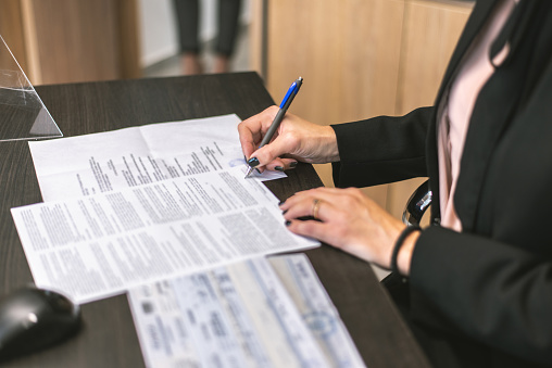 Closeup of a Business womanholding pen putting signature at paper. Caucasian businesswoman writing on paper signing document