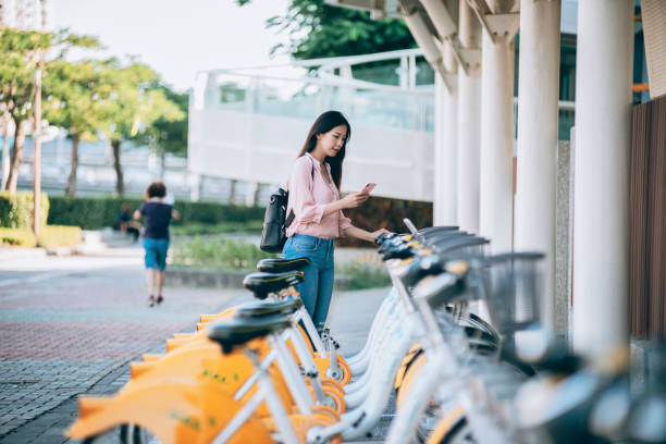 mujeres asiáticas alquilan bicicleta compartida en el centro de la ciudad - bikeshare fotografías e imágenes de stock