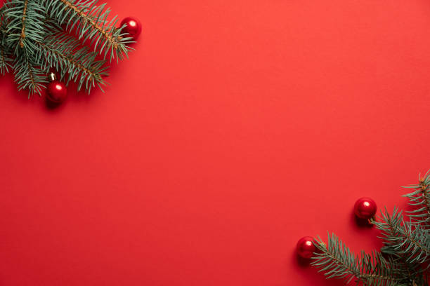 istock Christmas tree branches and red balls decoration on red background. Christmas greeting card, frame, banner mockup. Flat lay, top view, copy space. 1283051216