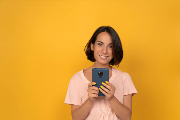 istock smiling young woman with smartphone in hand 1283052516