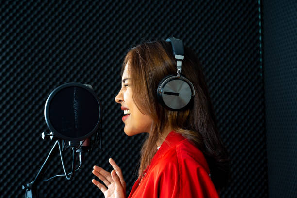 istock young attractive Asian woman musician singer in recoding studio with microphone. Performance arts concept. 1283052630