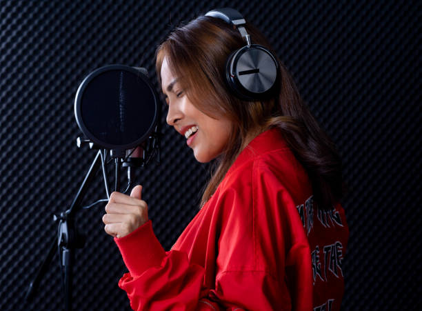 istock young attractive Asian woman musician singer in recoding studio with microphone. Performance arts concept. 1283052631