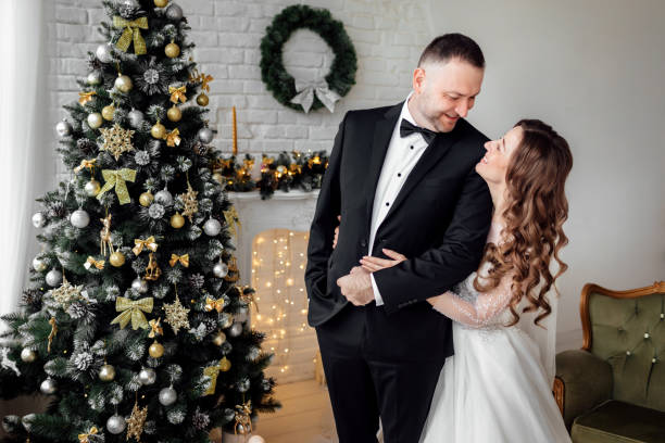 istock Young couple in love bride and groom posing in studio on background decorated with Christmas tree in their wedding day at Christmas. Enjoy a moment of happiness and love. 1283059310