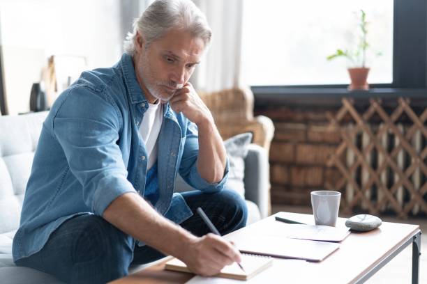istock Man in casual clothes working with financial documents while sitting on sofa at home. 1283064157