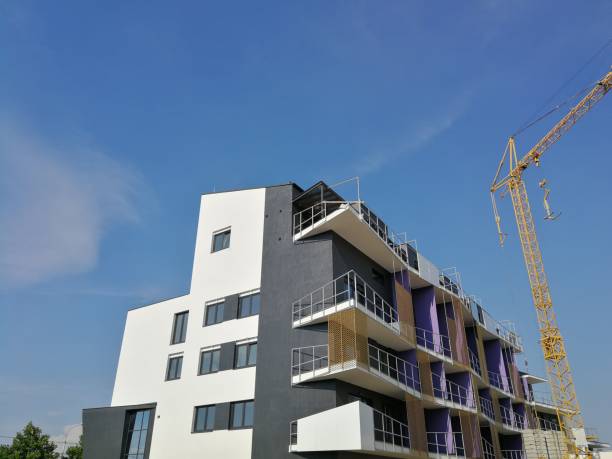 istock New multi-storey apartment building with a white and gray facade, with balconies, next to which stands a construction crane 1283064496
