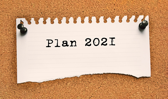 Paper note written with PLAN 2021 inscription on cork board