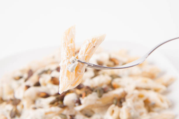 Pasta with blue cheese and cream sauce, sprinkled with roasted pumpkin seeds eaten with a fork