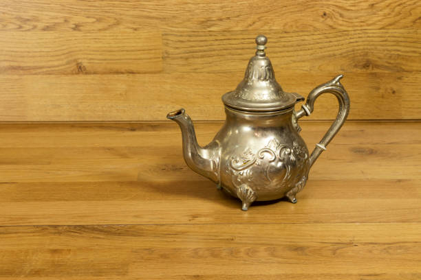 Black cast iron teapot isolated on reflective white background. The composition is at the right of an horizontal frame leaving useful copy space for text and/or logo at the left. Predominant colors are black and white. High resolution 42Mp studio digital capture taken with Sony A7rii and Sony FE 90mm f2.8 macro G OSS lens