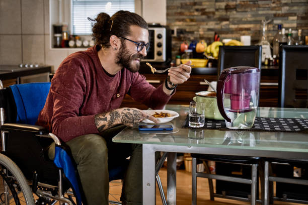istock Freelance worker in wheelchair working on laptop while eating at home 1283071954