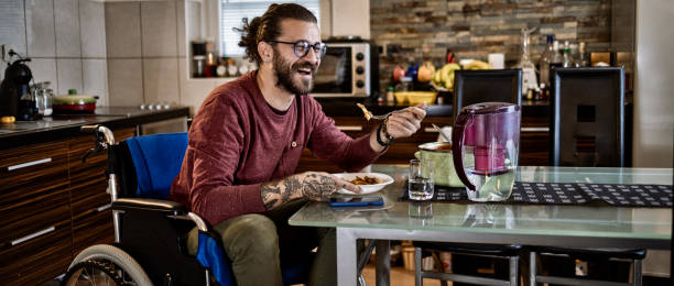 istock Freelance worker in wheelchair working on laptop while eating at home 1283071985