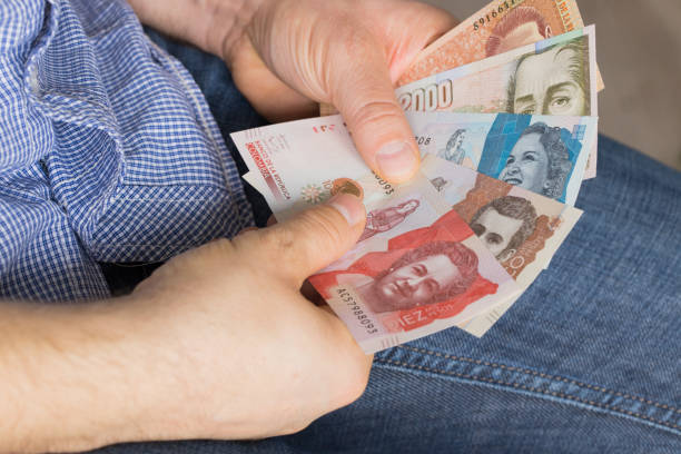 um homem segurando um pacote de dinheiro em suas mãos, vários pesos colombianos - beak buying currency exchanging - fotografias e filmes do acervo