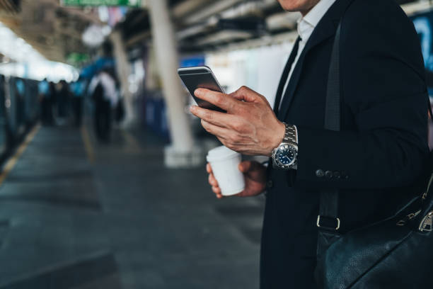 istock Unrecognizable business man holding a disposable coffee cup and using phone at train station 1283075224