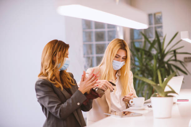 istock Two young women talking in an office wearing a protective face mask 1283076308