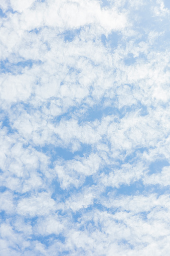 Blue sky with soft white clouds, beautiful nature background with copy space, full frame vertical composition with copy space