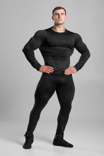 istock Muscular man in black compression sportswear on gray background 1283079318