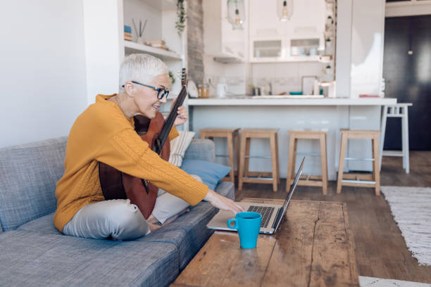 Senior woman learning to play guitar online