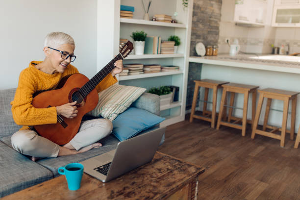 istock Senior woman using an online tutorial to learn to play guitar 1283079373